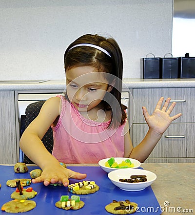 A Young Girl Decorating Biscuits. Stock Photo