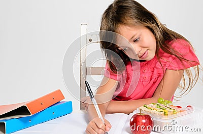 Young girl does her homework on table Stock Photo