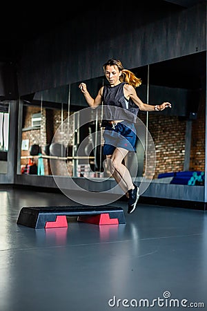 Young girl is doing fitness and different exercises in the gym. Sport is health. Many sports equipment on e background. Themes of Stock Photo