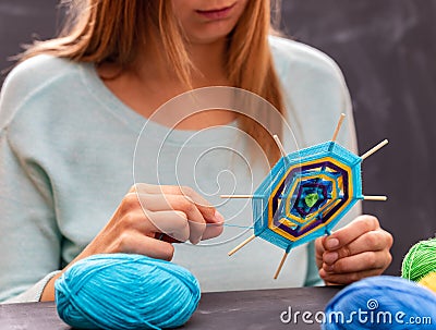 Young girl is doing handmade mandala out of colored yarn. Stock Photo