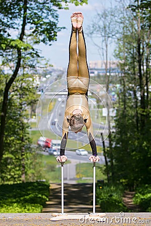 Young girl doing strength gymnastic exercises workout in a beautiful suit outdoors in a park. Stock Photo