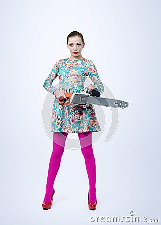 Young girl in dress holding electric saw on background. Woman with tools concept Stock Photo