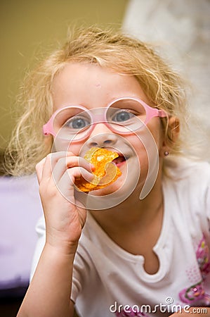 Young girl eating chips making funny face Stock Photo