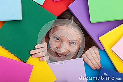 Young girl emerging from beneath books Stock Photo