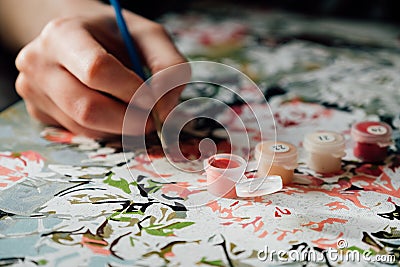 Young girl enjoying painting by numbers picture. Creative hobby. Leisure activity at home during self-isolation COVID-19 Stock Photo