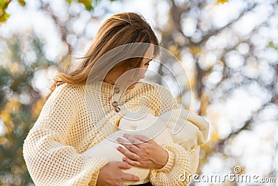 Young girl feeds newborn baby in park Stock Photo