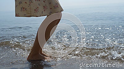 Young girl feet jumping on sea waves close up. Slim woman splashing ocean water. Stock Photo