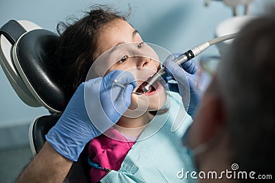 Young girl on the first dental visit. Senior pediatric dentist treating patient girl teeth at the dental office Stock Photo