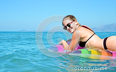 Young girl floating on inflatable mattress in the sea. Stock Photo