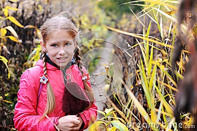 The young girl with a frightened face stands among the abandoned garden Stock Photo