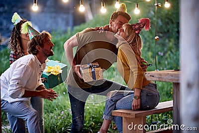 A young girl is getting presents and congratulations from friends at her birthday party at cottage porch. Vacation, nature, Stock Photo