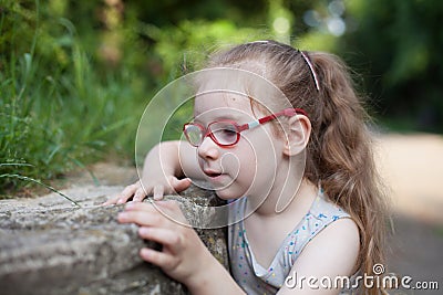 young girl with glasses playing in the park with stones and insects Stock Photo