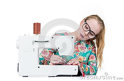 Young girl with glasses sews on a sewing machine, isolated on white background Stock Photo