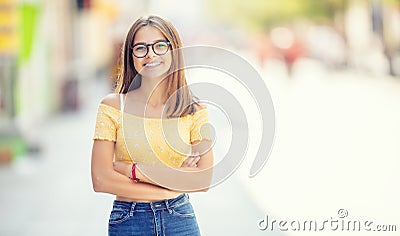 Young girl with glasses standing in somewhere the city smiling and looking at the camera Stock Photo