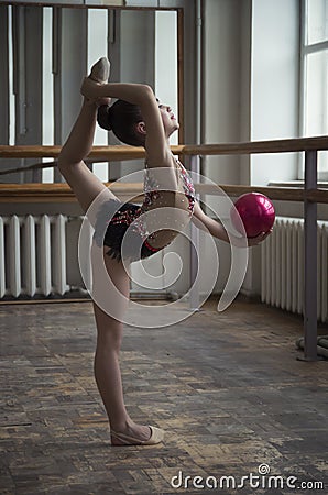 Young girl gymnast with a red ball in the hall Stock Photo