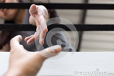 Young girl Hands reaching out from metal bars helping people Stock Photo