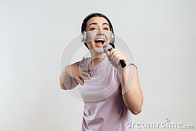 Young girl in headphones expressively sings Stock Photo