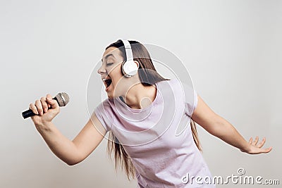 Young girl in headphones expressively sings Stock Photo