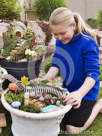 Young girl helping to make fairy garden in a flower pot Stock Photo