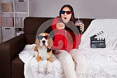 A young girl with her dog beagle in 3 d glasses watching a movie at home. Stock Photo