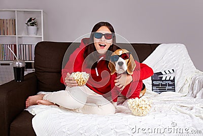 A young girl with her dog beagle is watching a movie at home. Stock Photo