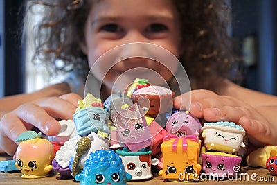 Young girl holding Shopkins a range of tiny collectable toys manufactured by Moose Toys Editorial Stock Photo