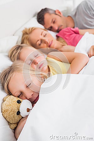 Young girl holding a teddy bear next to her sleeping family Stock Photo