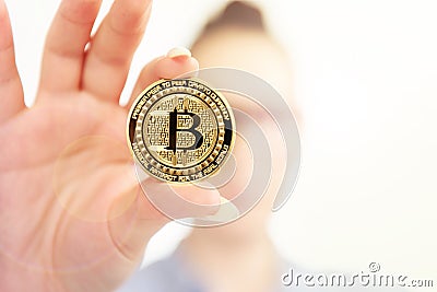 Young girl holds bitcoin in her fingers on background flares Stock Photo