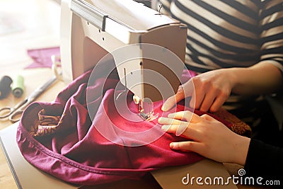 A young girl learns from her mother how to repair her clothes with a vintage sewing machine at home Stock Photo