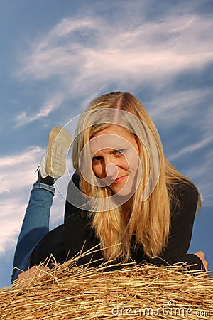 Young girl lie prone on straw bale, front view Stock Photo