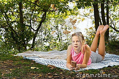 A young girl lies on a rug in the park. Autumn picnic. young girl lying on a blanket in the autumn forest Stock Photo