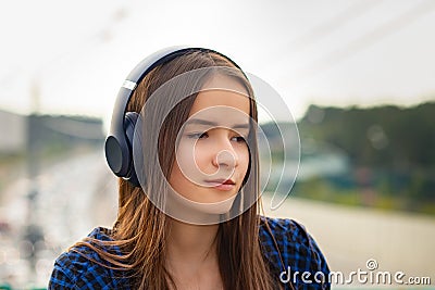 Young girl listening to MP3 player on the street with headphones, smilin Stock Photo