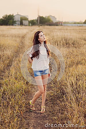Young girl with long brown hair stay at the meadow. Stock Photo