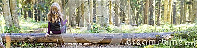 Young girl with long hair sitting on a tree log in autumn forest Stock Photo