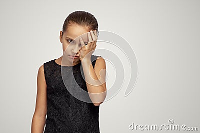 Young girl looks upset at the camera and closes her face with her hand in shame. Concept of failure, loss, frustration Stock Photo