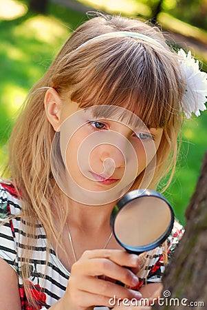 Young girl with magnifying glass in the park Stock Photo