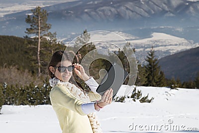 Young girl makes selfie photos with a tablet in winter Stock Photo