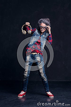 Young girl with makeup of senior woman. Elderly granny holding headphones in hand. Stock Photo