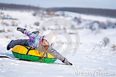 Little girl enjoying snow tubing at sunny weather Stock Photo