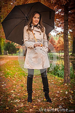 young girl in overcoat in forest. Fashion woman in coat in park. Slim young fashion model wearing white coat outdoor. Stock Photo