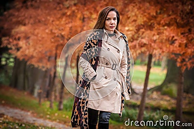young girl in overcoat in forest. Fashion woman in coat in park. Slim young fashion model wearing white coat outdoor. Stock Photo
