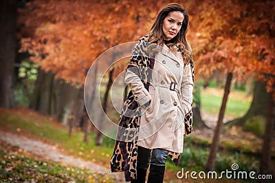 young girl in overcoat in forest. Fashion woman in coat in park. Slim young fashion model wearing white coat outdoor. Stock Photo