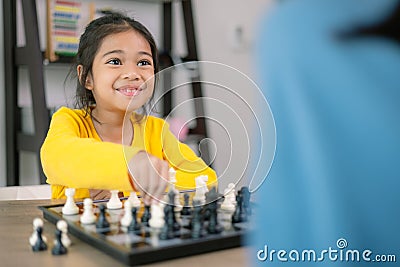 A young girl is playing a game of chess with an adult Stock Photo