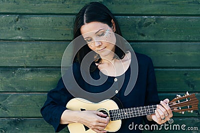 A young girl is playing ukulele Stock Photo