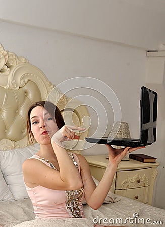 A young girl pointing at laptop and ironic wrinkling his nose Stock Photo