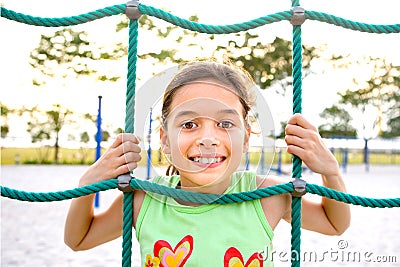 Young girl poking head through climbing rope Stock Photo