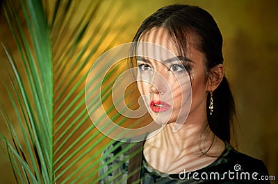 A young girl portrait with shadows from with palm leaves dressed up as a cosplay woman in jungle Stock Photo