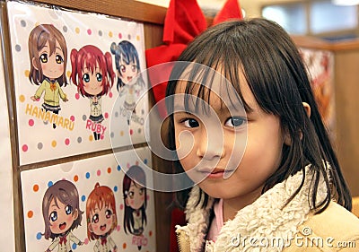 YOUNG GIRL POSES BESIDE ANIME PICTURE Editorial Stock Photo