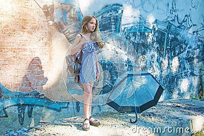 Young girl posing against a wall with graffiti, the Sun, jeans stands at the painted walls. Stock Photo