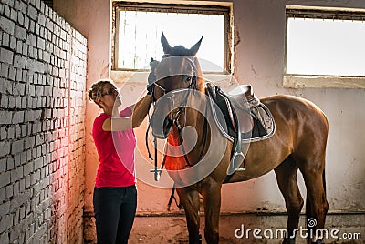 A young girl prepares her horse for riding Stock Photo